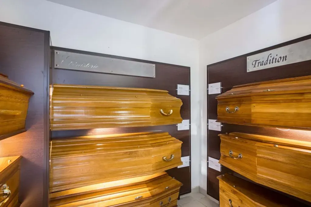 Salle d'exposition présentant plusieurs modèles de cercueils en bois.