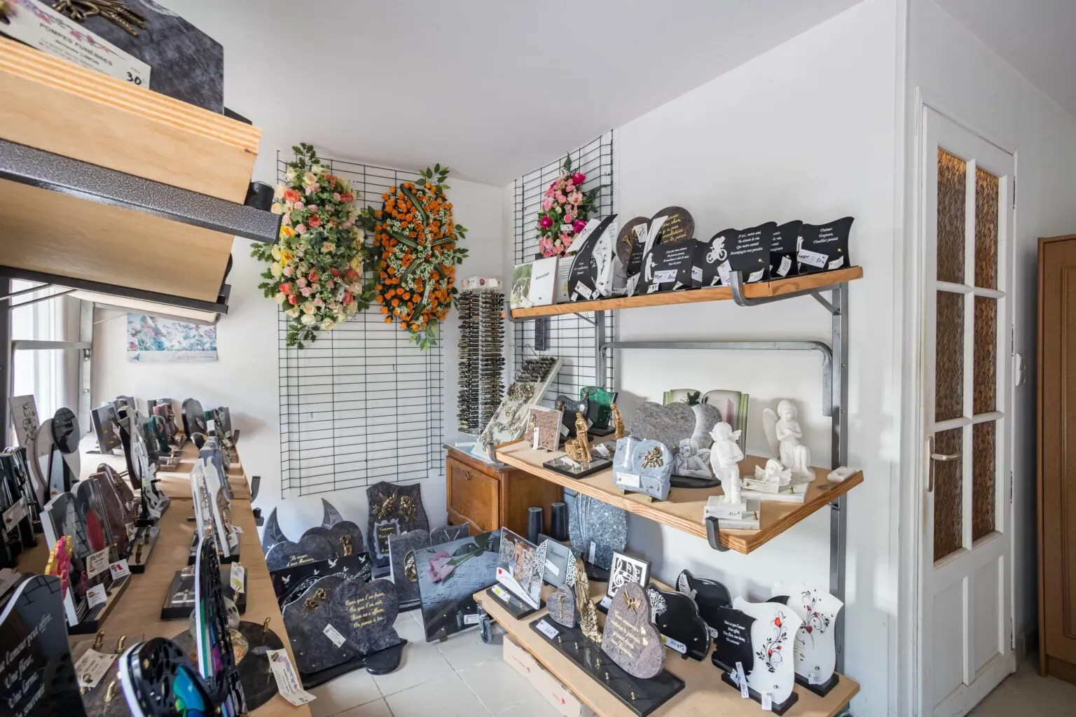 Vue d'ensemble de la boutique avec plaques mortuaires et fleurs.