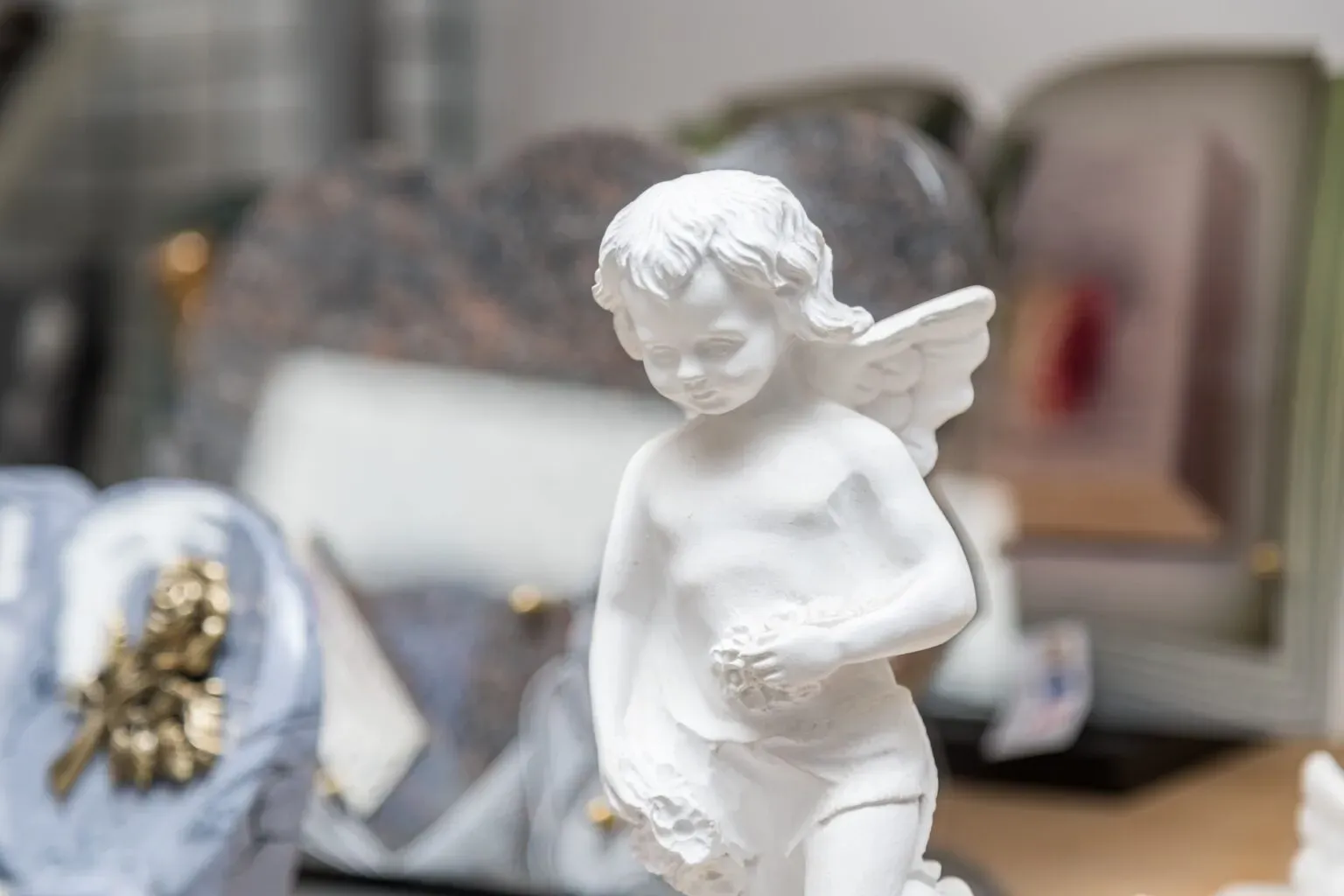 Statuette d'ange blanc exposée en rayon d'articles funéraires.