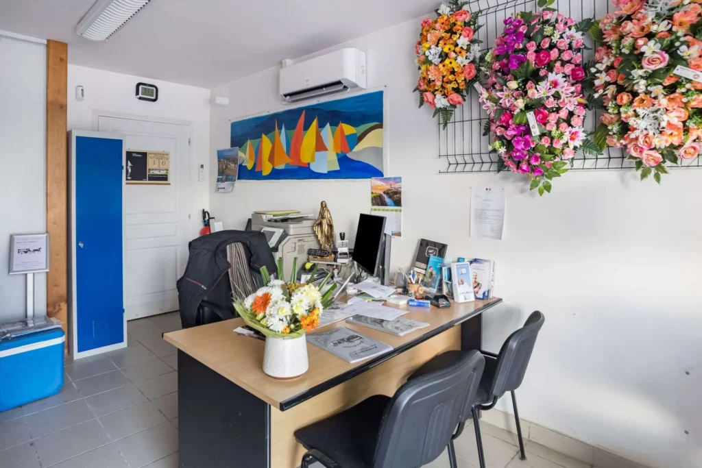 Bureau d'accueil avec poste informatique, fleurs murales et compositions.