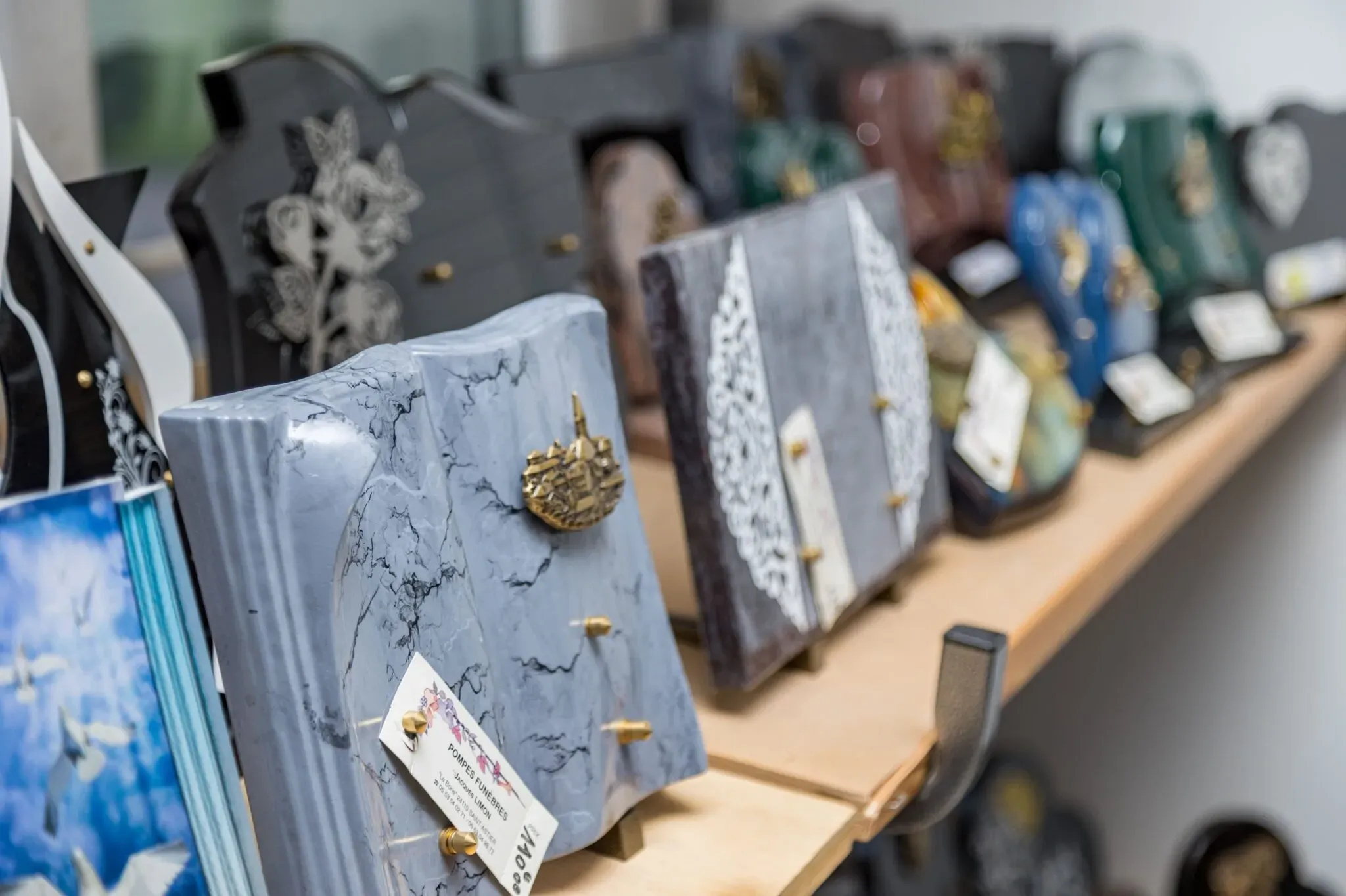 Gros plan sur différentes plaques funéraires personnalisées exposées en rayon.