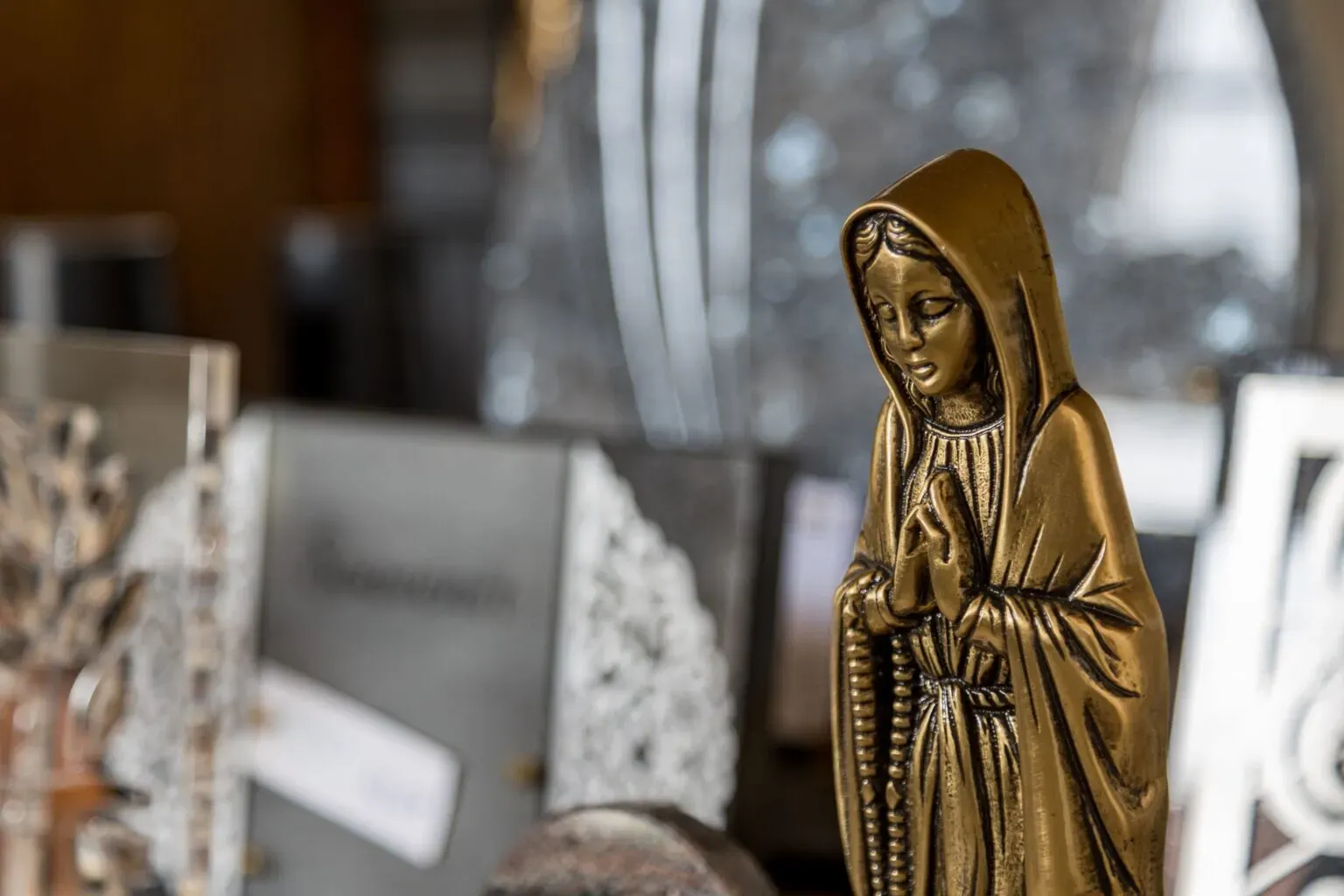 Gros plan sur une statuette dorée de la Vierge Marie en prière.